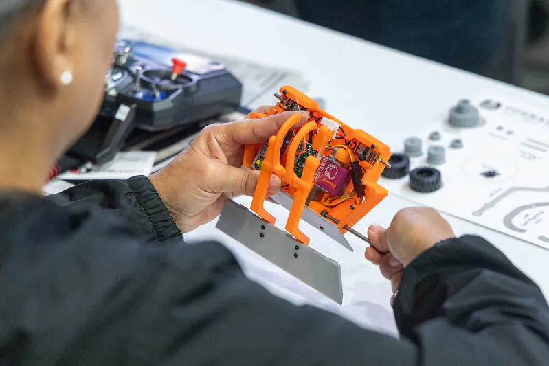 Attendee examining a compact robot at ai+expo 2026