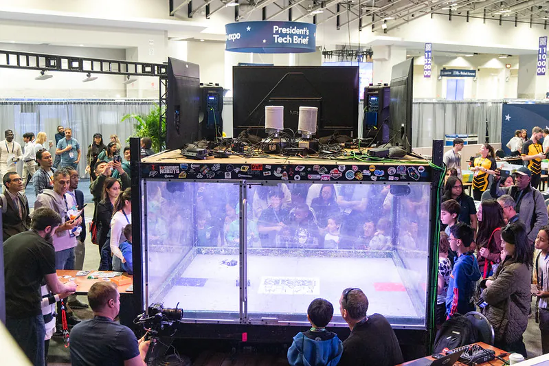 Robot combat demonstration surrounded by spectators at ai+expo 2026